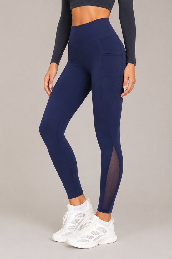 Model in donkerblauwe sportlegging met mesh-inzetstukken, steekzakken, witte sokken en sneakers.