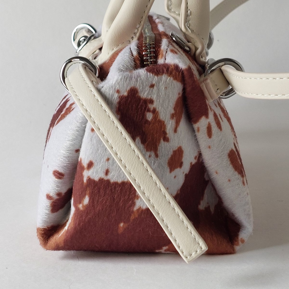 schoudertas dames koe print bruin wit - een design met zilverkleurige details - opvallende crossbody tas trendy statement bag - compacte handtas met rits