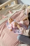 Een baby-pop in een roze outfit met bloemen op een aankleedkussen.