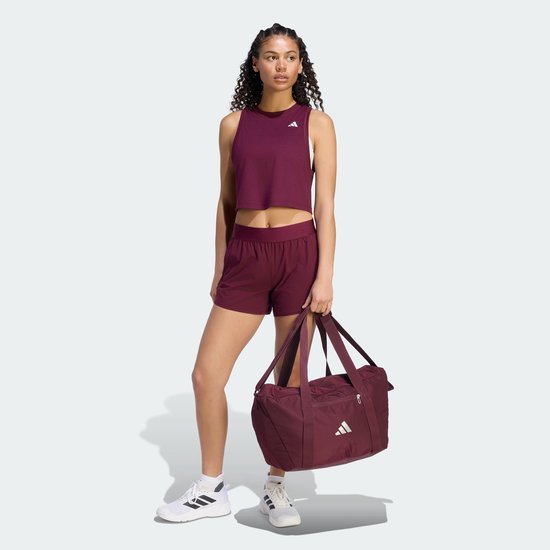 Vrouw in bordeauxrode sportkleding met een bordeauxrode sporttas.