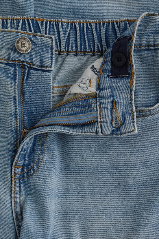 Detail van de ritssluiting en tailleband van een lichtblauwe jeans.