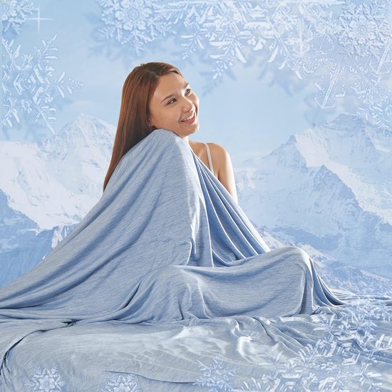 Vrouw in blauwe, zachte deken op besneeuwde bergachtergrond met sneeuwvlokken.