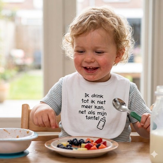 Witte slabbetje met tekst "Ik drink tot ik niet meer kan, net als mijn tante!". Baby aan tafel met een bordje fruit.