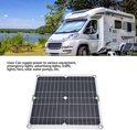 Zwart zonnepaneel met rasterpatroon, bevestigingsringen en groene tape, naast een camper.