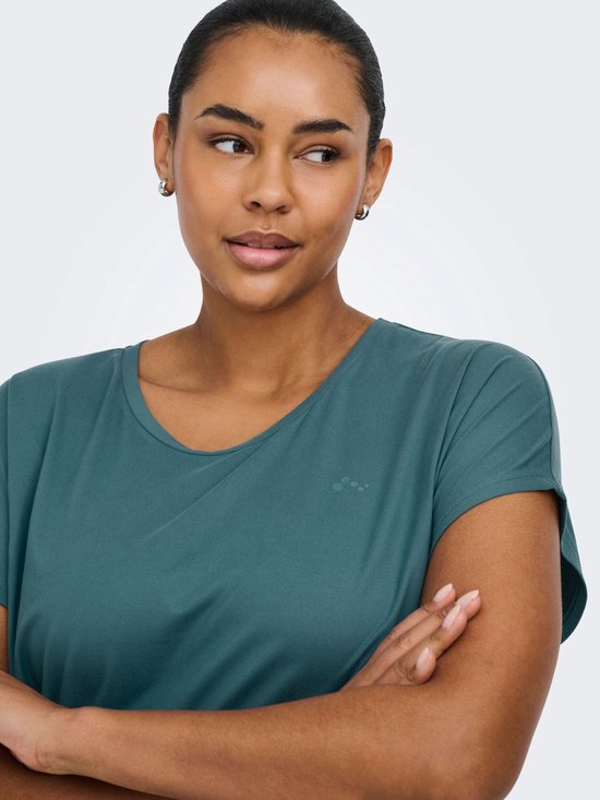 Close-up van een model die een petrolkleurig sportshirt met korte mouwen draagt, met de armen over elkaar.