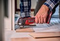 Man met rood-zwarte multitool werkt aan een houten vloer.