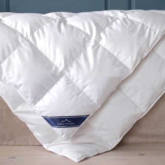 Witte donzen dekbed met ruitstiksels en donkerblauwe band met Nordic Paradise logo.