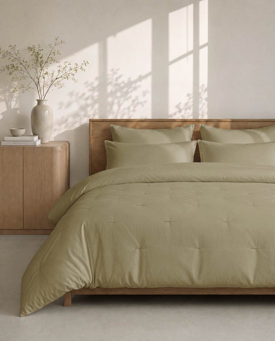 Olijfgroen HOOMstyle dekbed en kussens op een bed met houten hoofdbord.
