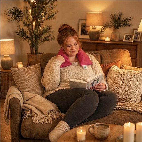 Een vrouw leest een boek met een rood kersenpitkussen om haar nek.