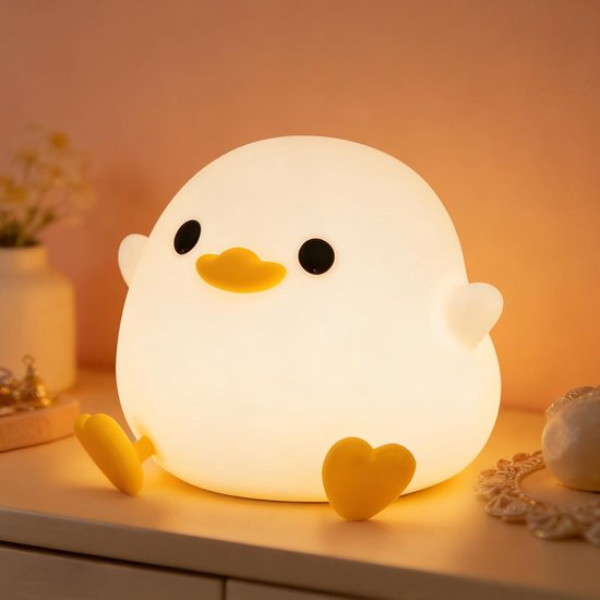 Wit, zacht siliconen eendje nachtlampje op een nachtkastje met zachte verlichting.