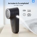 Zwarte pluizenverwijderaar met USB-C kabel, 2-3 uur opladen, 30 min draadloos gebruik.