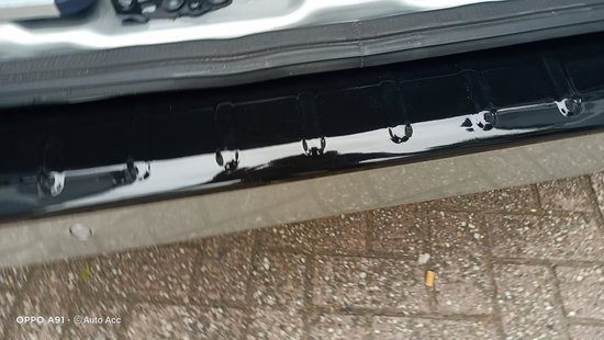 Glanzend zwarte bumperplaat met reliëf, close-up.