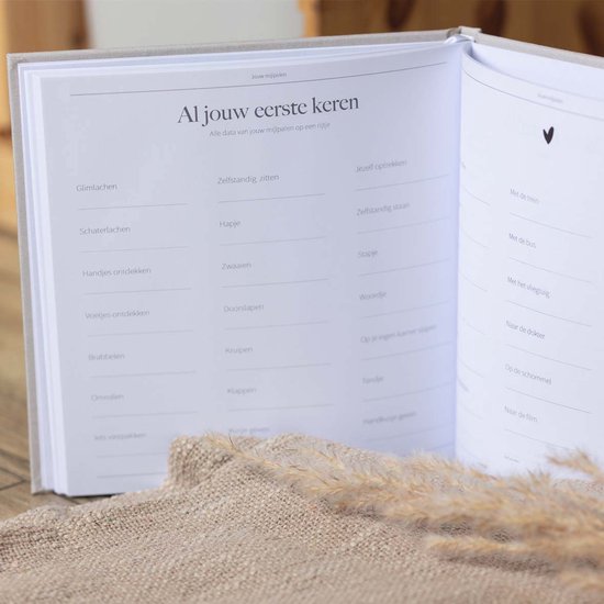 Open dagboek met pagina's 'Al jouw eerste keren' met lijsten voor mijlpalen en ervaringen.