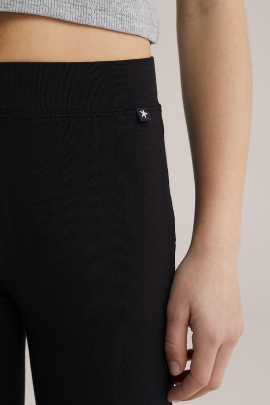Detail van een zwarte legging met een klein wit sterretje op een zwart label bij de tailleband.