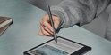 Hand met grijze BOOX styluspen schrijft op een e-reader.