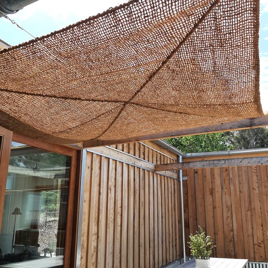 Bruin kokosvezel schaduwdoek, 5x5 meter, bevestigd boven een houten terras en pergola, met metalen oogjes.