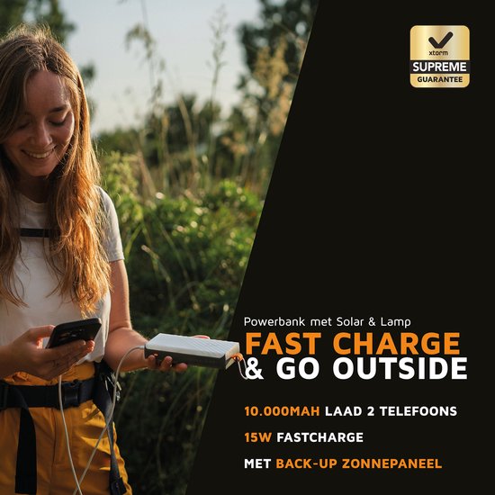Vrouw met zonnebril en muts houdt smartphone vast, naast Xtorm powerbank met zonnepaneel.