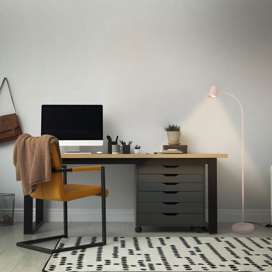 Beige vloerlamp met gebogen arm verlicht een bureau met een computer en gele stoel.