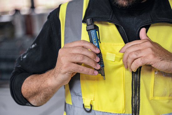 Man in geel hesje stopt een blauwe en zwarte Bosch spanningstester in zijn borstzak.