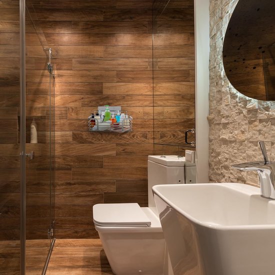 Zelfklevend roestvrijstalen doucherek met diverse toiletartikelen, gemonteerd aan een houten betegelde muur in een badkamer.
