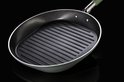 Ovale grillpan met zwarte grillstrepen, lichtgroene buitenkant en groene steel, op zwarte achtergrond.