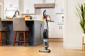 De zwarte BISSELL CrossWave vloerreiniger staat op een houten vloer in een moderne keuken.