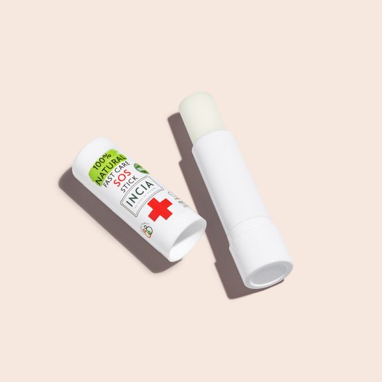 Witte SOS stick van INCIA met rode kruis en groene tekst '100% NATURAL FAST CARE SOS STICK' naast een open stick.