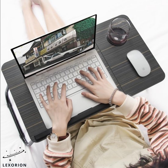 Een persoon met een gestreepte trui gebruikt een laptop en muis op de grijze laptoptafel. Een glas staat ernaast.