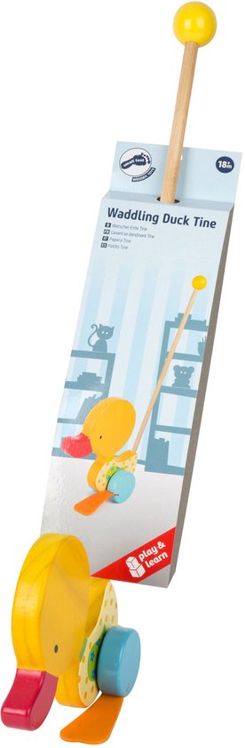 Houten duwfiguur van een gele eend met rode en oranje accenten, staand op blauwe wielen. Met stok en gele knop aan het uiteinde. Verpakking toont 'Waddling Duck Tine'.