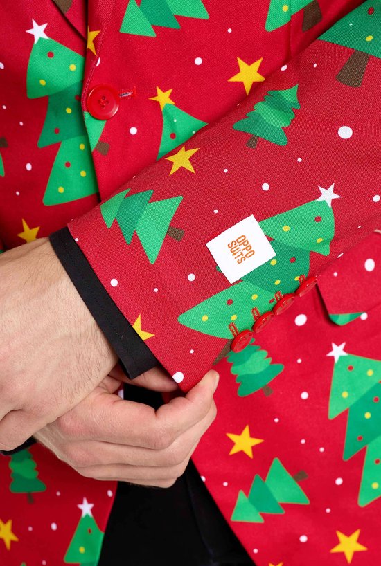 Close-up van mouw van rode kerstblazer met witte sterren en groene kerstbomen, met Opposuits label.
