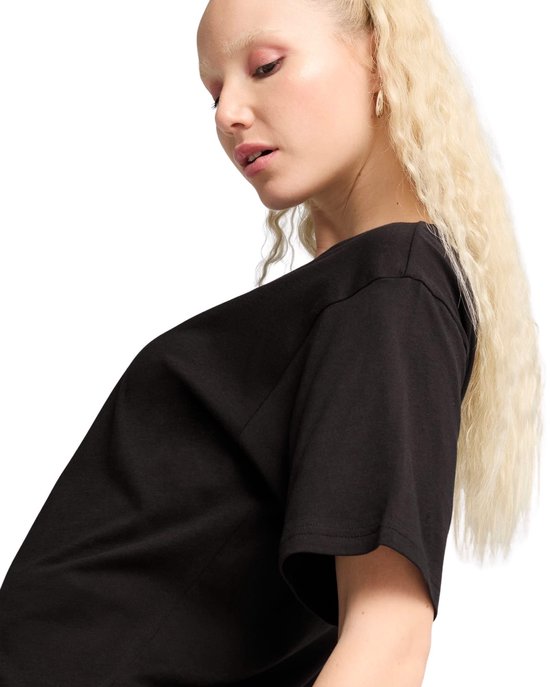 Een vrouw met blond haar draagt een zwarte oversized T-shirt.