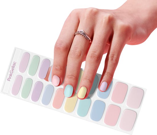 Een hand met een ring, die een vel met pastelkleurige nagelstickers vasthoudt. Kleuren: lichtroze, mintgroen, lavendel, lichtblauw, pastelgeel.