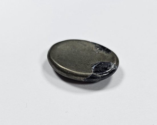 Een gladde, ovale, donkergrijze steen met glinsterende metalen delen aan de rechterzijde.