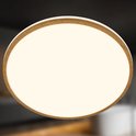 Close-up van een ronde plafondlamp met houten rand en een warm, crème-kleurig licht.