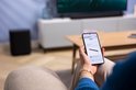 Telefoon met de 'Enchant Speaker' app, met een afbeelding van de speaker en bedieningselementen.