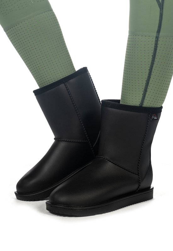 Bottes noires toutes saisons avec coutures apparentes, portées avec un legging vert.