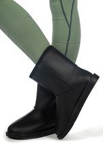 Bottes noires toutes saisons portées avec un legging vert foncé perforé.
