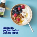 Kom met yoghurt, blauwe bessen, frambozen, granola en honing. Flesje Arctic Blue Omega 3 er naast. "Ideaal in yoghurt of zo van de lepel."