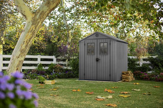 Abri de jardin Keter Darwin gris avec double porte, fenêtres, situé dans un jardin avec pelouse et arbres.