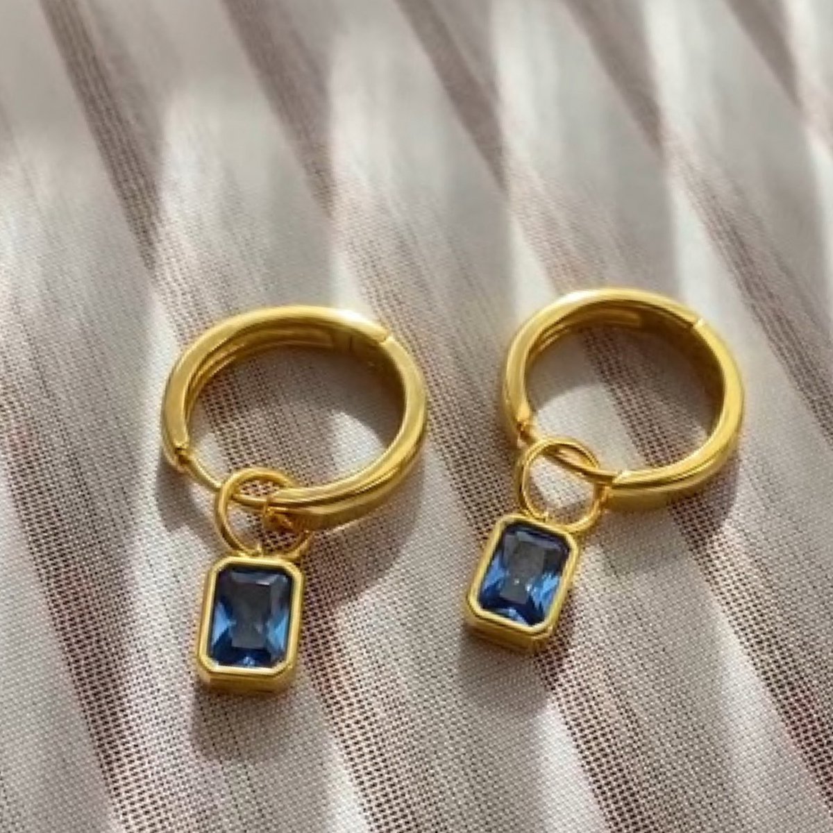Bling-it zilveren oorring met blauwe steen. Materiaal: 925 sterling zilver, 14 karaat gouden laagje. Afmeting oorbel 2.5cm