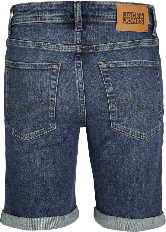 Donkerblauwe denim jongensshorts van Jack & Jones met opgerolde broekspijpen en een bruin logo-label op de achterkant.