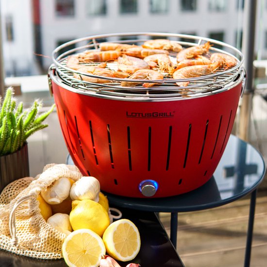 Rode LotusGrill met gegrilde garnalen, citroenen, knoflook en een plant.