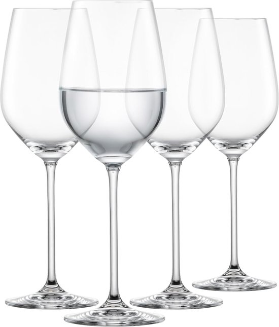 Quatre verres à vin élégants, hauts et transparents sur fond blanc. Un verre contient une petite quantité d'eau.