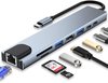 Zilveren USB-C hub met HDMI, Ethernet, USB-A, SD en Micro SD poorten, met kabels en geheugenkaarten ernaast.