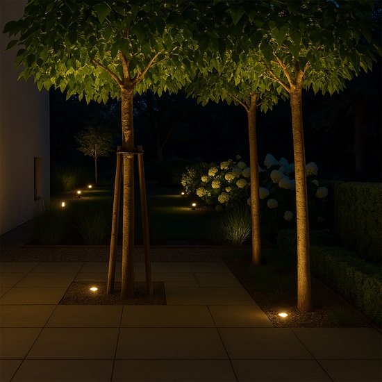 Verlichte tuin bij nacht met pad- en boomverlichting.