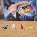 Monopoly speelstukken: vliegtuig, kluis, hoed en auto op een gevlochten ondergrond.
