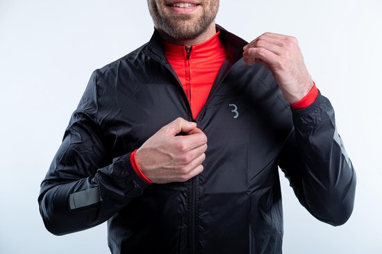 Dichtbij van een man die een zwart fietsjack met rode binnenzijde dichtritst.