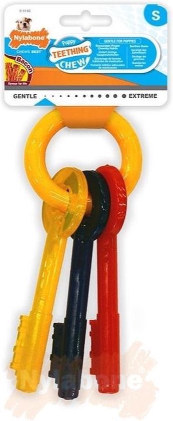 Verpakking met geel, rood en blauw sleutel speeltje, met 'Puppy Teething Chew' en 'Bacon flavour'.