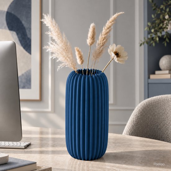 Marineblauwe, 3D-geprinte geribbelde vaas met droogbloemen op een kantoorbureau.