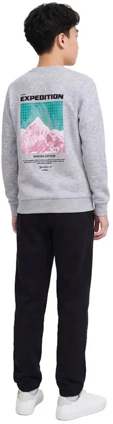 Jongen draagt grijze sweater met 'EXPEDITION WINTER EDITION' print van bergen en raster, met zwarte joggingbroek.